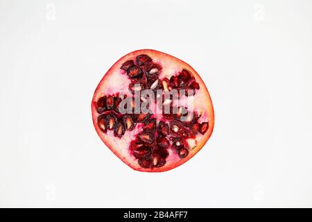 Close up of isolated cut half red shiny juicy pomegranate fruit seeds, white background with copy space for text Stock Photo