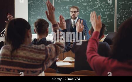 All students raising hands Stock Photo