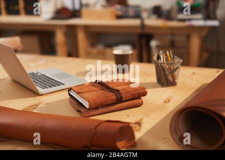 Leather notebooks on wooden table in modern craft workshop, horizontal no people shot Stock Photo