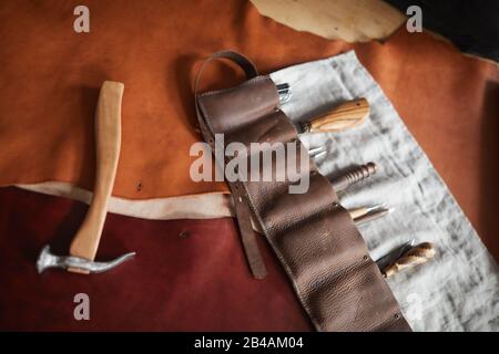 Horizontal from above shot of case with tools, hammer and pieces of leather material on table Stock Photo