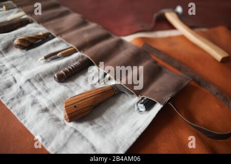 Horizontal high angle shot of various tools in handmade case, claw hammer and pieces of leather material on table Stock Photo