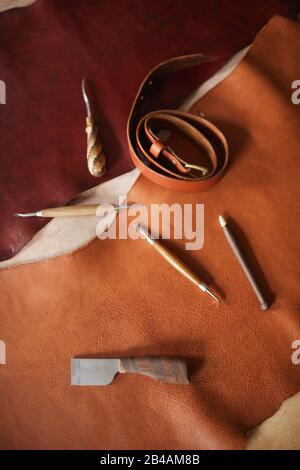 Vertical from above flat lay shot of various tools for craftwork with leather materials on table Stock Photo