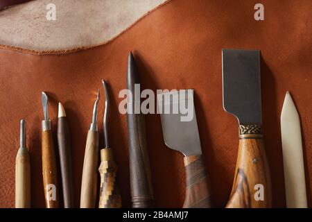 Horizontal from above flat lay shot of various tools for craftwork with leather materials lying on table in raw Stock Photo