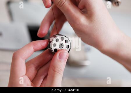 Replacing threads on a drum in a sewing machine. A leather craftsman produces leather goods on a sewing machine. Handmade work. To close. Stock Photo
