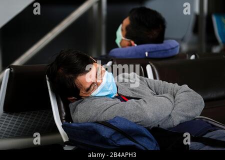 Hong Kong, China. 06th Mar, 2020. Travellers wearing face masks as a precaution against the outbreak of Coronavirus rest at the waiting area at Hong Kong International Airport.As the Coronavirus (Covid-19) continues to spread all over the world, many countries have tighten up travel restrictions. Credit: SOPA Images Limited/Alamy Live News Stock Photo