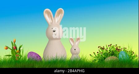 two easter bunnys stand on a meadow with easter eggs and flowes Stock Photo