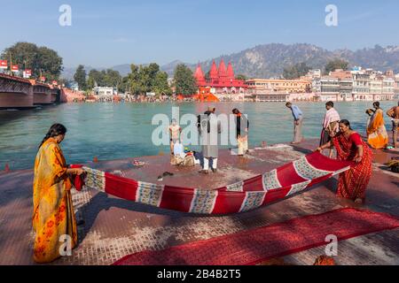 India, Uttarakhand, Haridwar, holy city of hinduism, Kumbh Mela Hindu pilgrimage, women drying a saree on by the Ganges and Bholanath Sevashram temple in the background Stock Photo