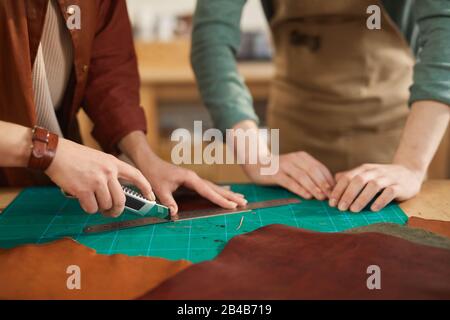 Hands of unrecognizable man and woman working together in modern leather craft workshop, copy space Stock Photo
