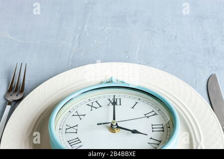 Alarm clock, White plate with fork and knife, Intermittent fasting concept, ketogenic diet, weight loss