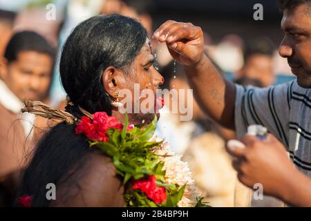 Malaysia, Selangor State, Batu Caves, Hindu festival Thaipusam procession, celebration of god Murugan, son of Shiva and Parvati, exhausted pilgrim receiving refreshing water on his face Stock Photo