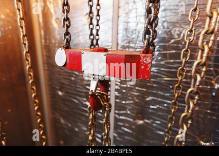 metallic chain handle with red hook in technical room. Crane cargo hook. Concept of maintenance and construction work. Stock Photo