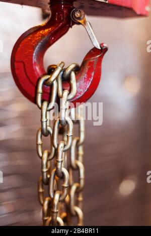 metallic chain handle with red hook in technical room. Crane cargo hook. Concept of maintenance and construction work. Stock Photo