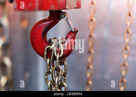 metallic chain handle with red hook in technical room. Crane cargo hook. Concept of maintenance and construction work. Stock Photo