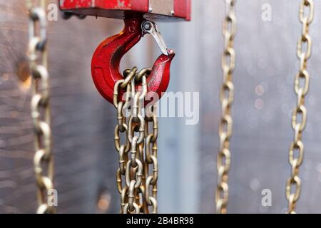 metallic chain handle with red hook in technical room. Crane cargo hook. Concept of maintenance and construction work. Stock Photo