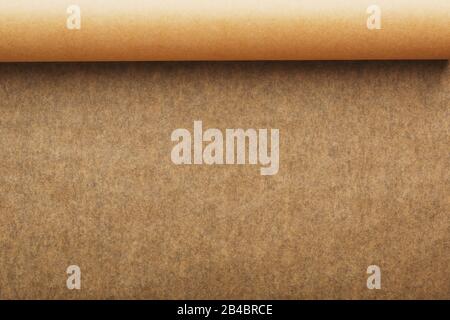 A roll of unfolded brown parchment paper, for baking food in on a dark background, top view. Papyrus Stock Photo