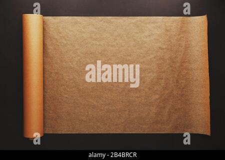 Vintage paper unfolded from a roll on a dark background. Papyrus, parchment, soft contrast Stock Photo