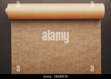 Vintage paper unfolded from a roll on a dark background. Papyrus, parchment, soft contrast Stock Photo