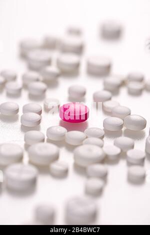 White medicinal pills with a single magenta pill in the center. Special medicine concept. Stock Photo