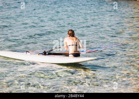 Young woman surfing on the Croatian coast, Cres / Croatia Stock Photo