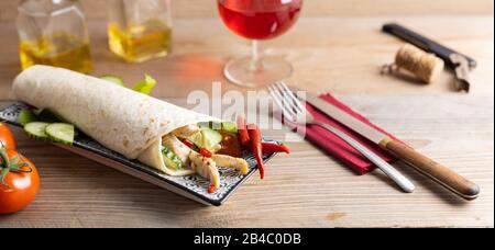 Chicken doner kebab with fresh vegetables on a wooden table with a glass of wine. Stock Photo