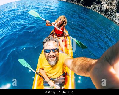 Selfie couple with top vertical point of view - happy active adult people enjoy kayak at the ocean - summer tourist in holiday vacation lifestyle - action camera and cheerful man and woman