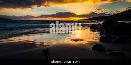 Travel and scenic sea landscape concept with sunrise or sunset time at the beach with amazing colors and beautiful sky with sun in background - wild nature outdoor with ocean and waves Stock Photo