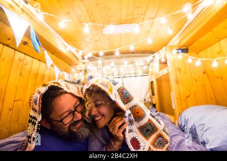 Couple in love and relationship have fun during a travel vacation with an old restored van to tiny house - van life concept for modern trendy people enjoying the freedom and the minimalism lifestyle Stock Photo