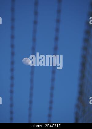 Sheerness, Kent, UK. 6th Mar, 2020. UK Weather: a waxing gibbous moon set against clear blue skies above Sheerness in Kent, seen through the razor wires of a security fence. Credit: James Bell/Alamy Live News Stock Photo