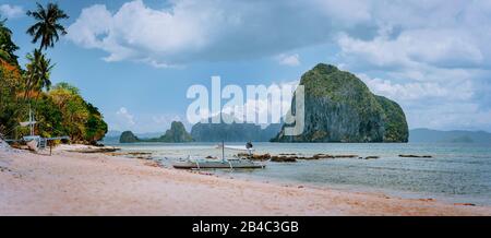 Panoramic view of El Nido coastline with traditional filippino boats on beach and Pinagbuyutan island in background. Palawan, Bacuit archipelago, Philippines. Stock Photo