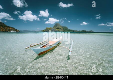 Traditional filippino fishing boat in shallow water lagoon at El Nido bay. Palawan island, Philippines. Stock Photo