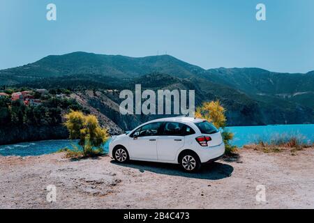 Vacation travel with car concept. Rental hired car in front of amazing bay with turquoise water. Discover Mediterranean Islands. Summer time holiday trip. Stock Photo