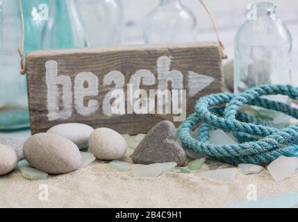 Nautical still life with wooden beach sign, stone heart and old rope Stock Photo