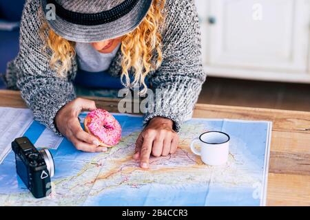 Alternative hipster travel young girl planning her next adventure trip on a island - paper old map on a wooden table and vintage camera - breakfast time for travelers people
