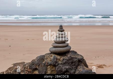 well balanced stone cairn on a lonely beach at the wild west coast of the portuguese algarve Stock Photo