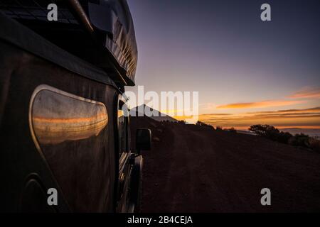 Close up of black of roas adventure car parked with beautiful sunset and mountain in background - concept of travel and discover wild places and enjoy alternative vacation adventure lifestyle Stock Photo