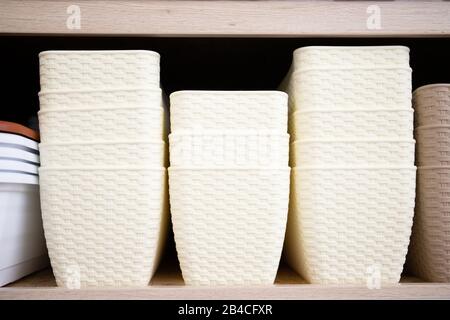 Beige plastic flower pots on a shelf. Stock Photo