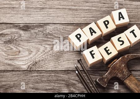 Hammer, nails and wooden cubes with inscriptions on the table. Papa Fest concept with copy space. Stock Photo