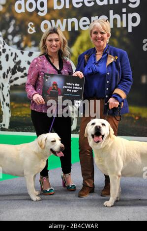 Cat Henstridge, TV personality and vet and Sussie Wiles (right), Kennel Club Assured Labrador breeder attend Crufts at the NEC Arena in Birmingham while supporting Defra's 'Petfished' campaign, which highlights how the public can be deceived by pet sellers before buying a new puppy or kitten and advises how to research and spot red flags. PA Photo. Picture date: Friday March 6th, 2020. On Monday April 6th 2020, the government's ban on third party sales of puppies and kittens comes into force. Known as 'Lucy's Law', it will help to end the terrible welfare conditions found in Stock Photo