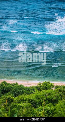 Man walking along of Nunggalan Beach. Big waves rolling on. Uluwatu, Bali, Indonesia. Stock Photo