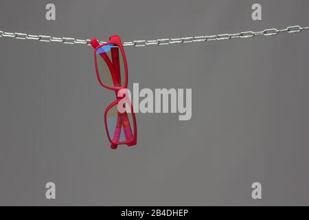 Colored glasses on a gray background and chain; glasses for vision correction; lenses to read or see from afar; Glasses can improve people's vision. Stock Photo