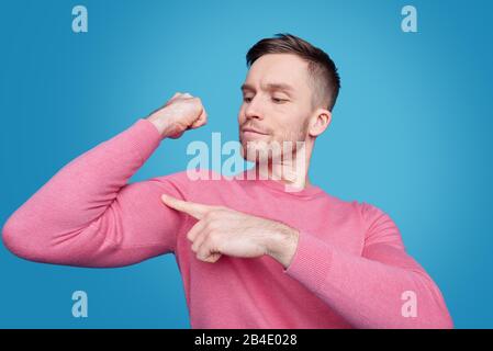 Successful young sporty man in casualwear pointing at his muscle on shoulder with proud expression in front of camera Stock Photo