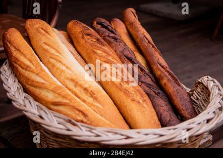 Wicker basket full of baguettes, tasty delicious crusty bread in bakery shopfront Basket with a baguette Stock Photo