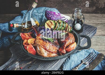 Fried pickled duck legs with a side dish of vegetables . Grilled zucchini, red cabbage and spices on a wooden table. Stock Photo
