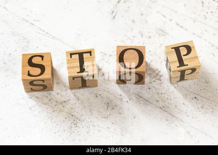 Four wooden cubes with word STOP on white working board.. Stock Photo