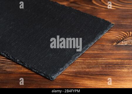 Crockery slate, black stone on a wooden background. Close up. Stock Photo