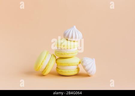 Yellow macarons and white marshmallows on a peach pastel background. Place for text. Stock Photo