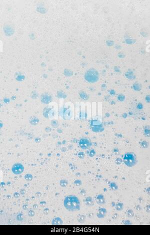 White foam with small bubbles popping in blue water Stock Photo
