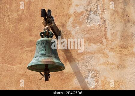 Bell in front of ocher house wall, Greece, Crete, Spinalonga Island, Kalydon Stock Photo