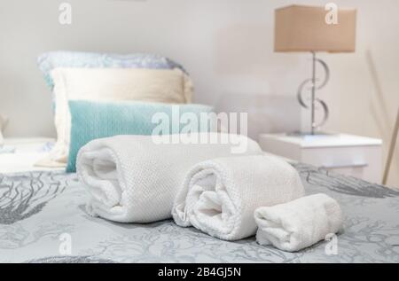 Rolls of towels symmetrically on the bed in the bedroom Stock Photo