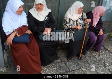 Muslim women wearing hijab wait at bus stop. A hijab is a veil worn by some Muslim women in the presence of any male outside of their immediate family, which usually covers the head and chest.wait at bus stop Stock Photo